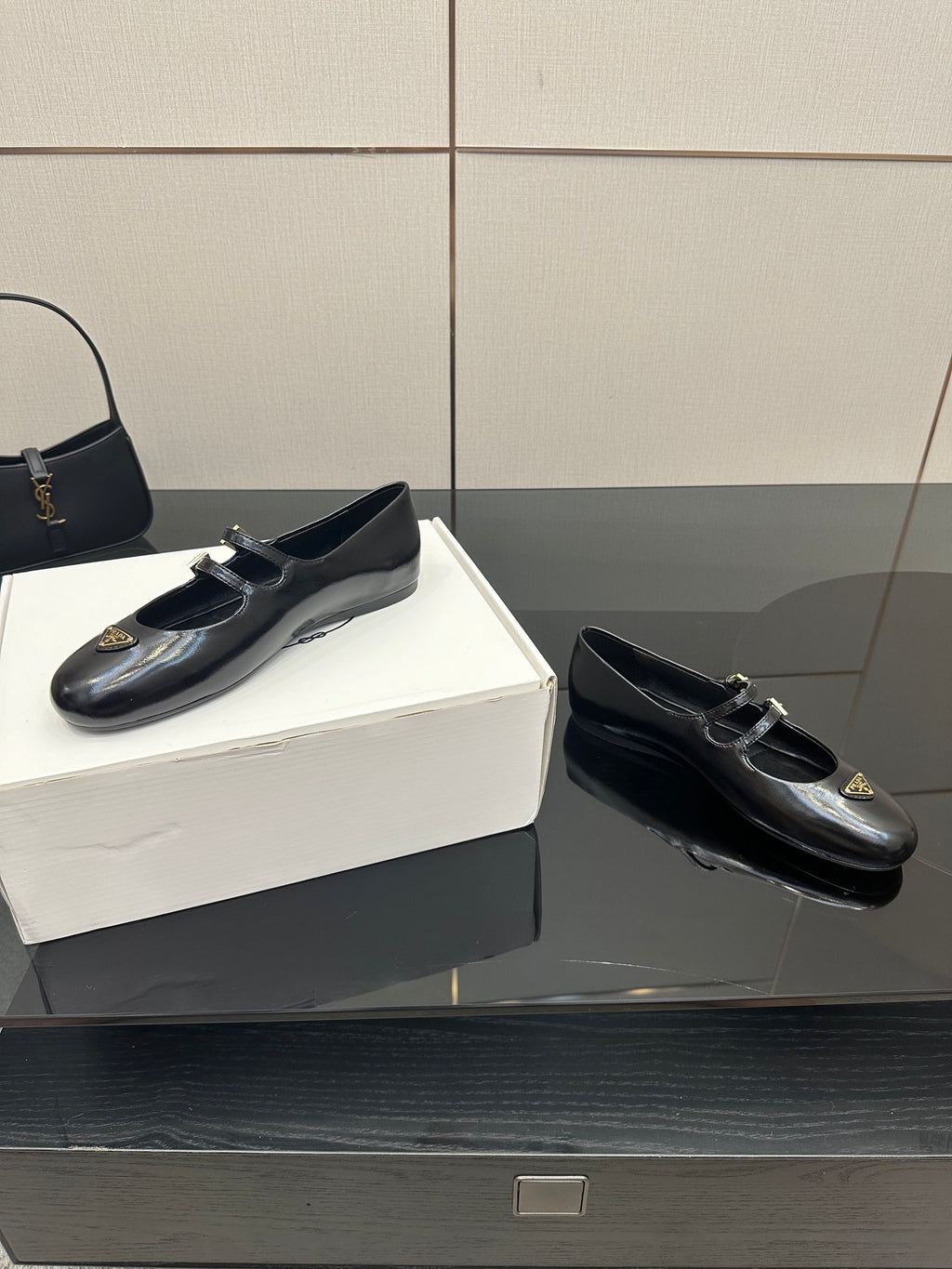 Prada women's black leather loafers pair with gold-tone buckle detail, side view