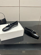 Prada women's black leather loafers pair with gold-tone buckle detail, side view