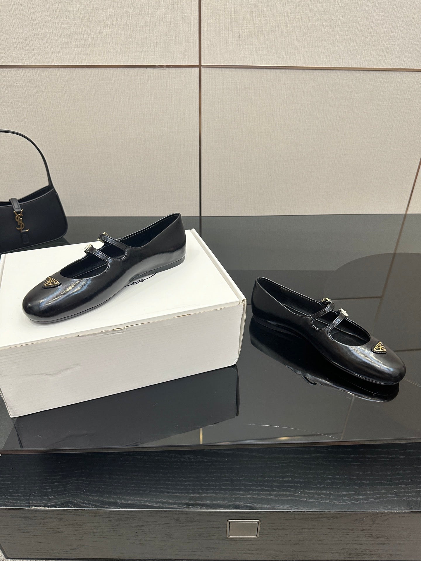 Prada women's black leather loafers pair with gold-tone buckle detail, side view