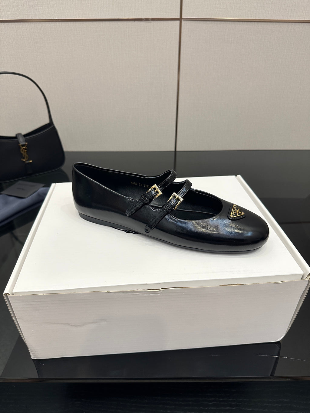 Prada women's black leather loafer with strap buckles and gold emblem, top view