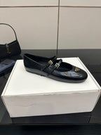 Prada women's black leather loafer with strap buckles and gold emblem, top view