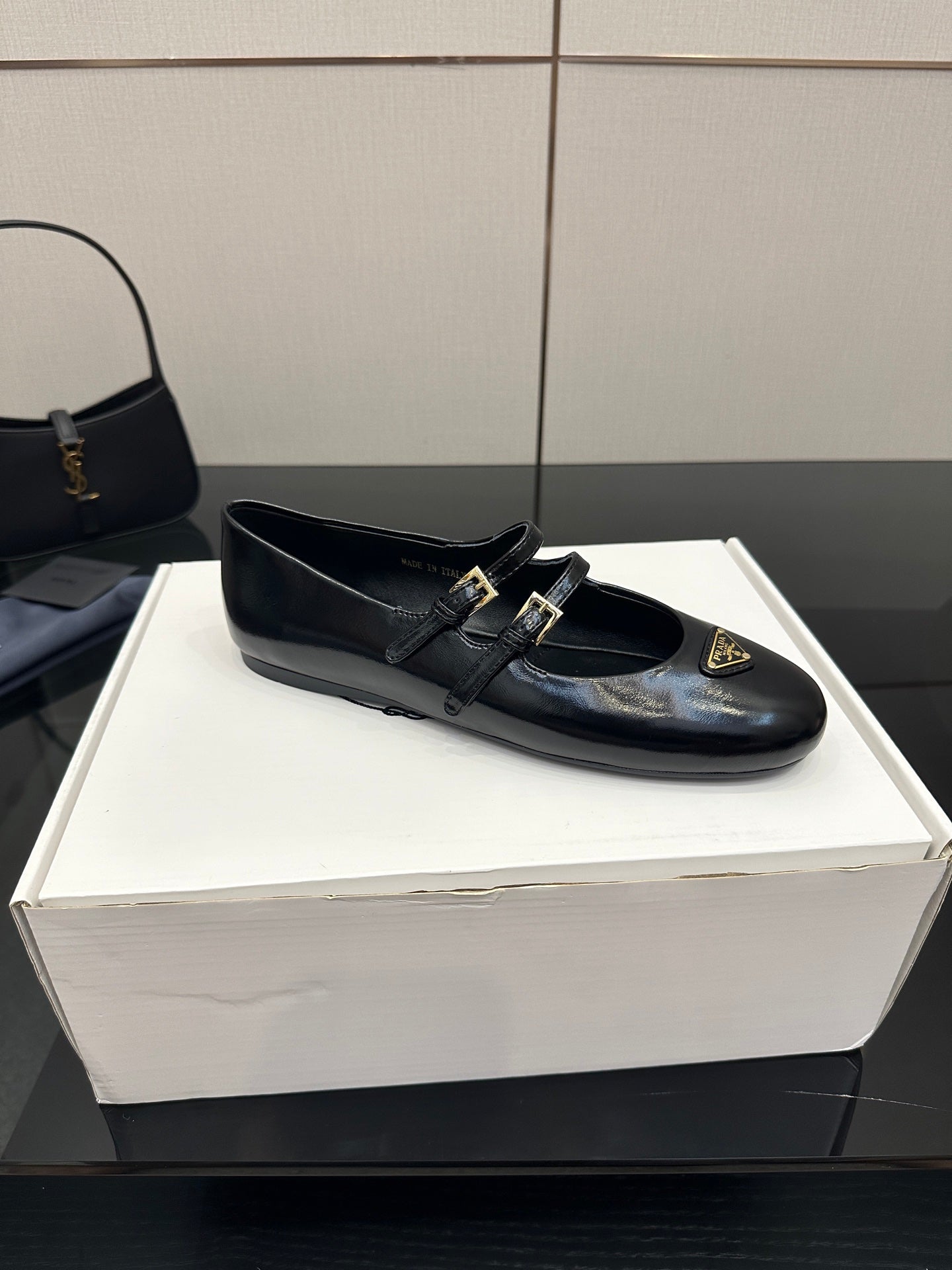 Prada women's black leather loafer with strap buckles and gold emblem, top view
