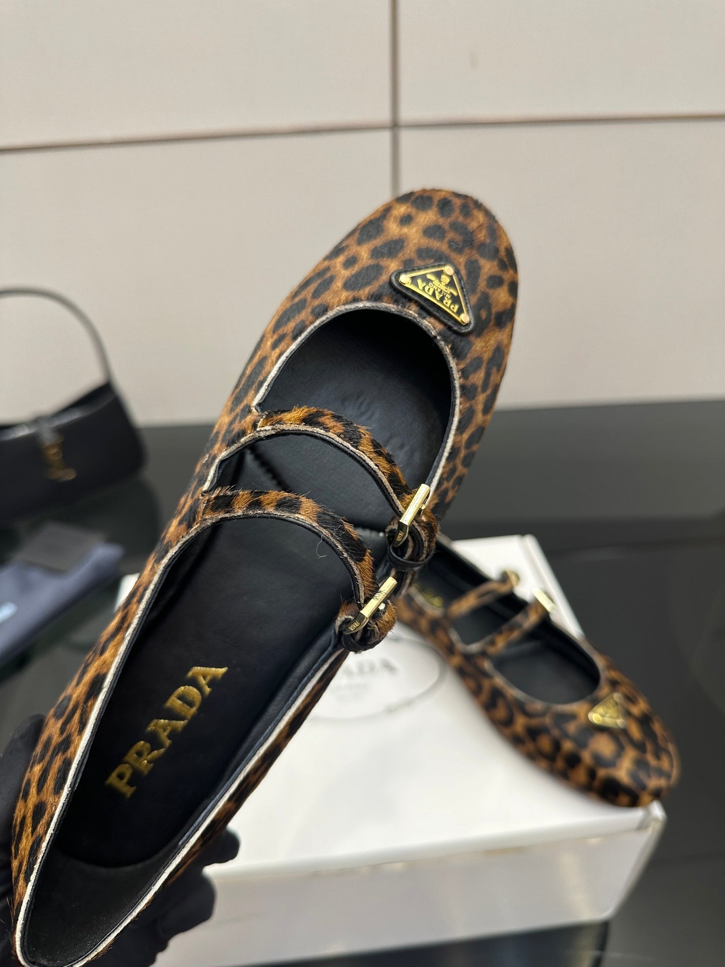 Prada leopard-print flat loafer close-up, black lining and gold buckle strap