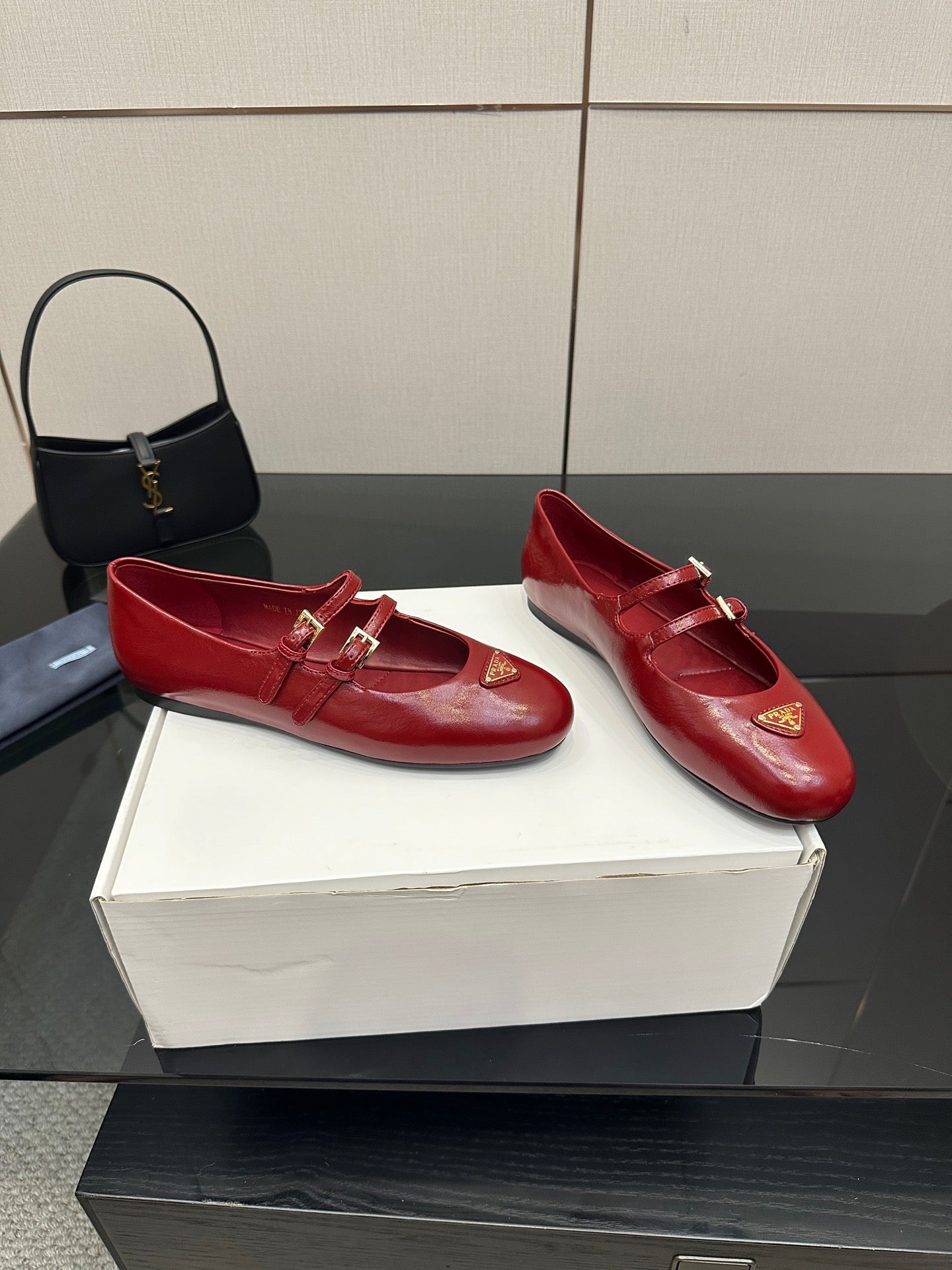 Prada women’s red leather loafers with gold buckle strap and logo plaque, side view
