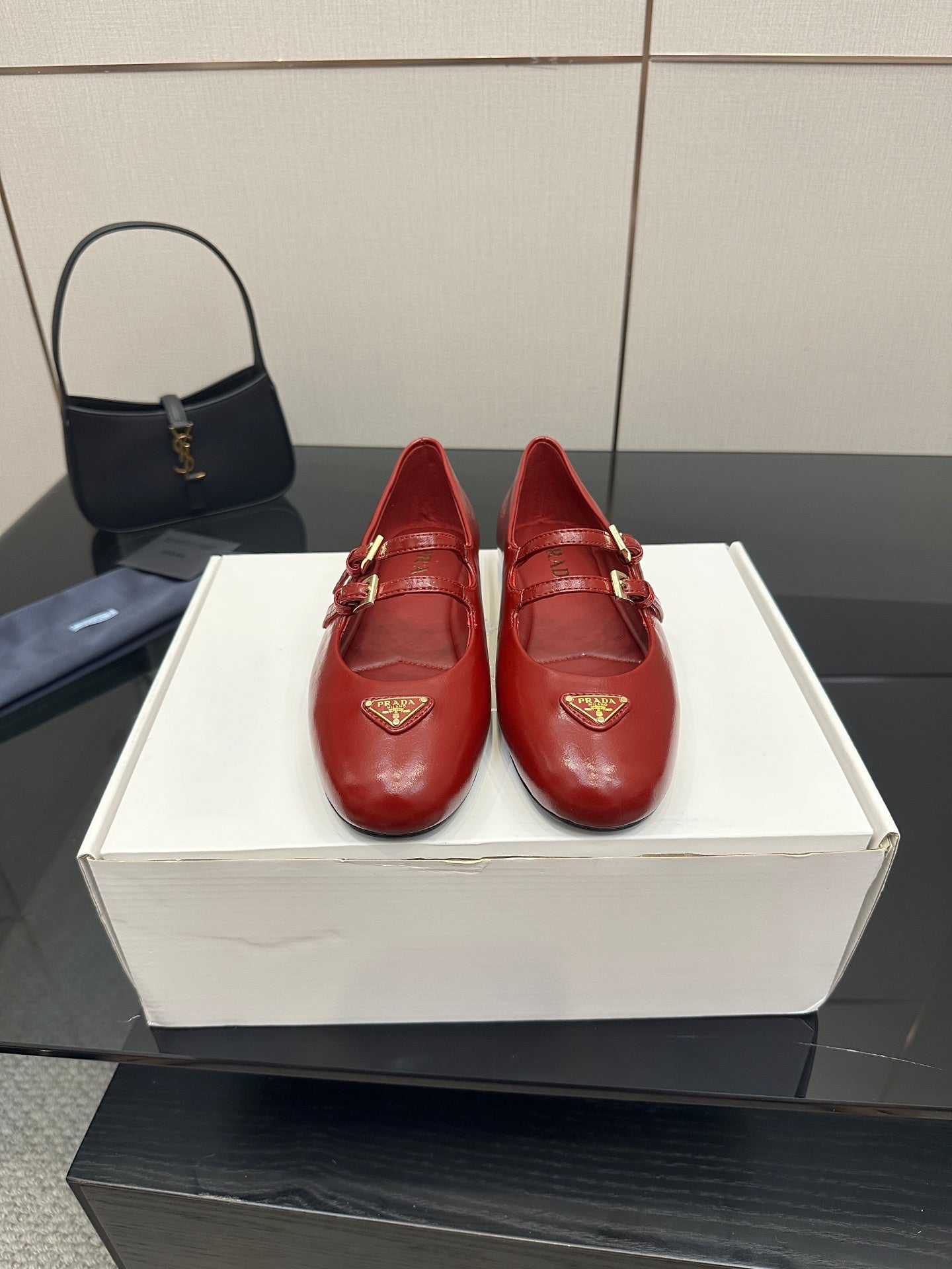 Prada women’s red leather loafers with gold logo plaque and strap buckles, front view