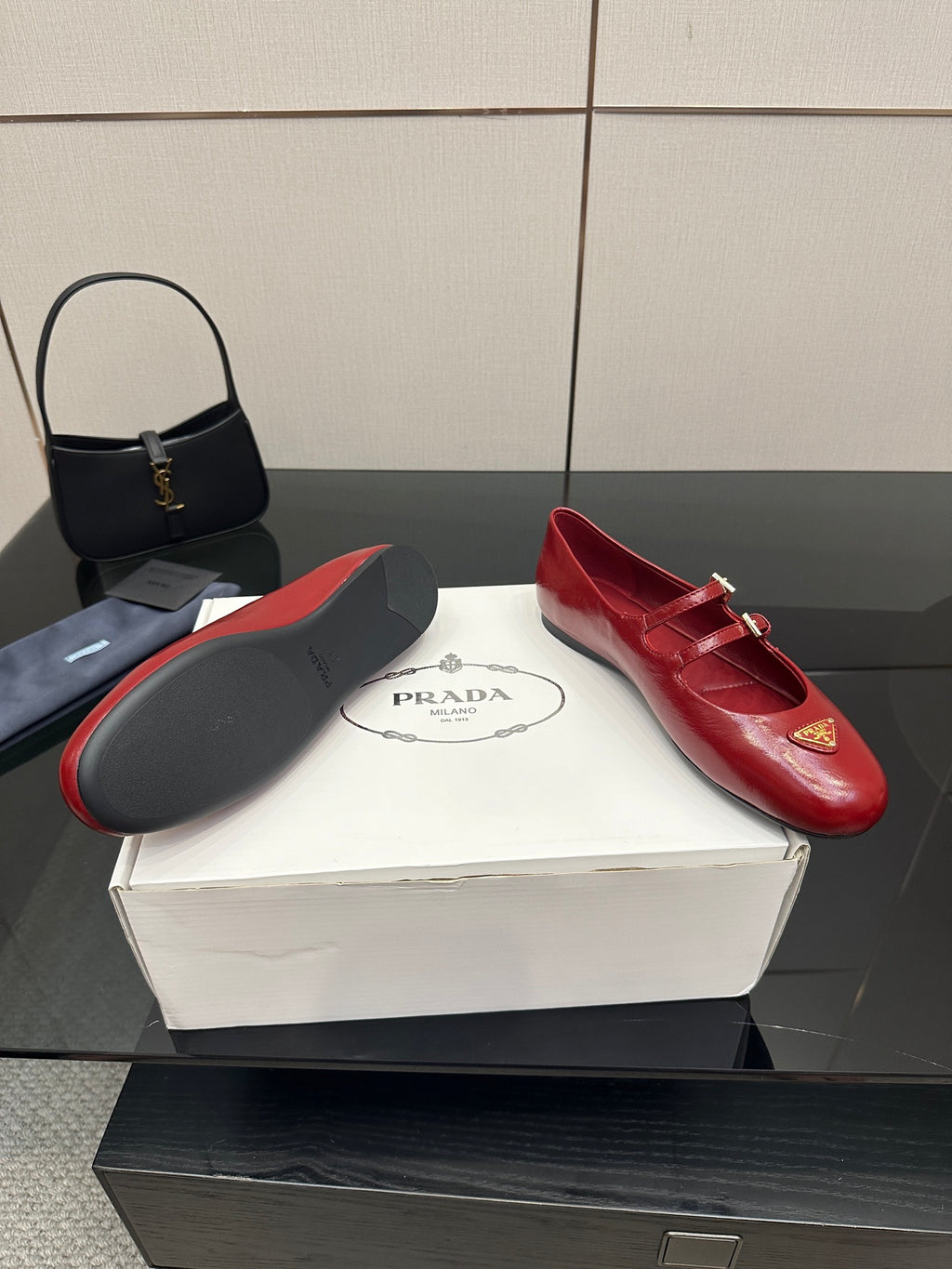 Prada women’s red leather loafers with gold logo plaque and buckled strap, side angle