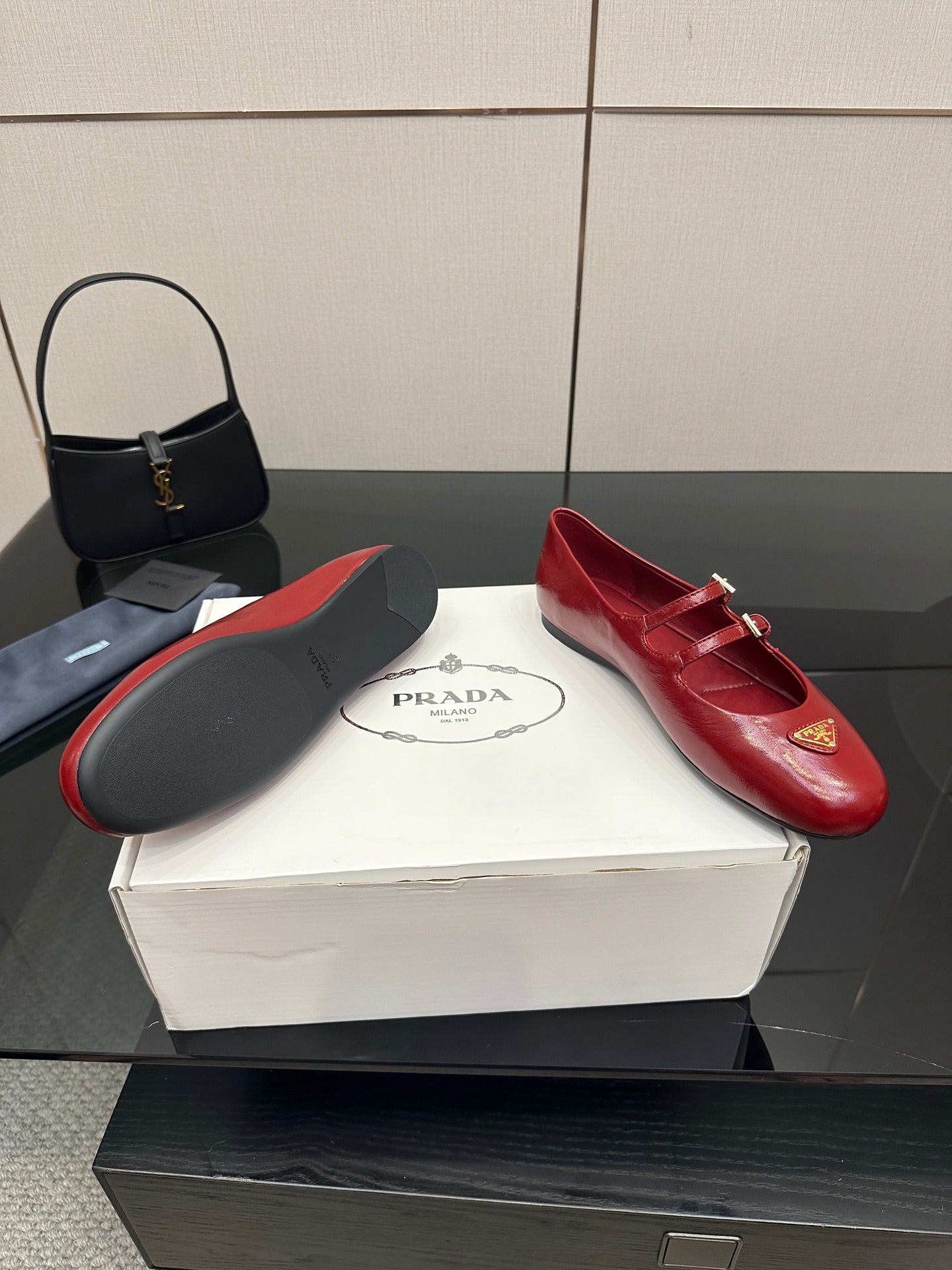 Prada women’s red leather loafers with gold logo plaque and buckled strap, side angle