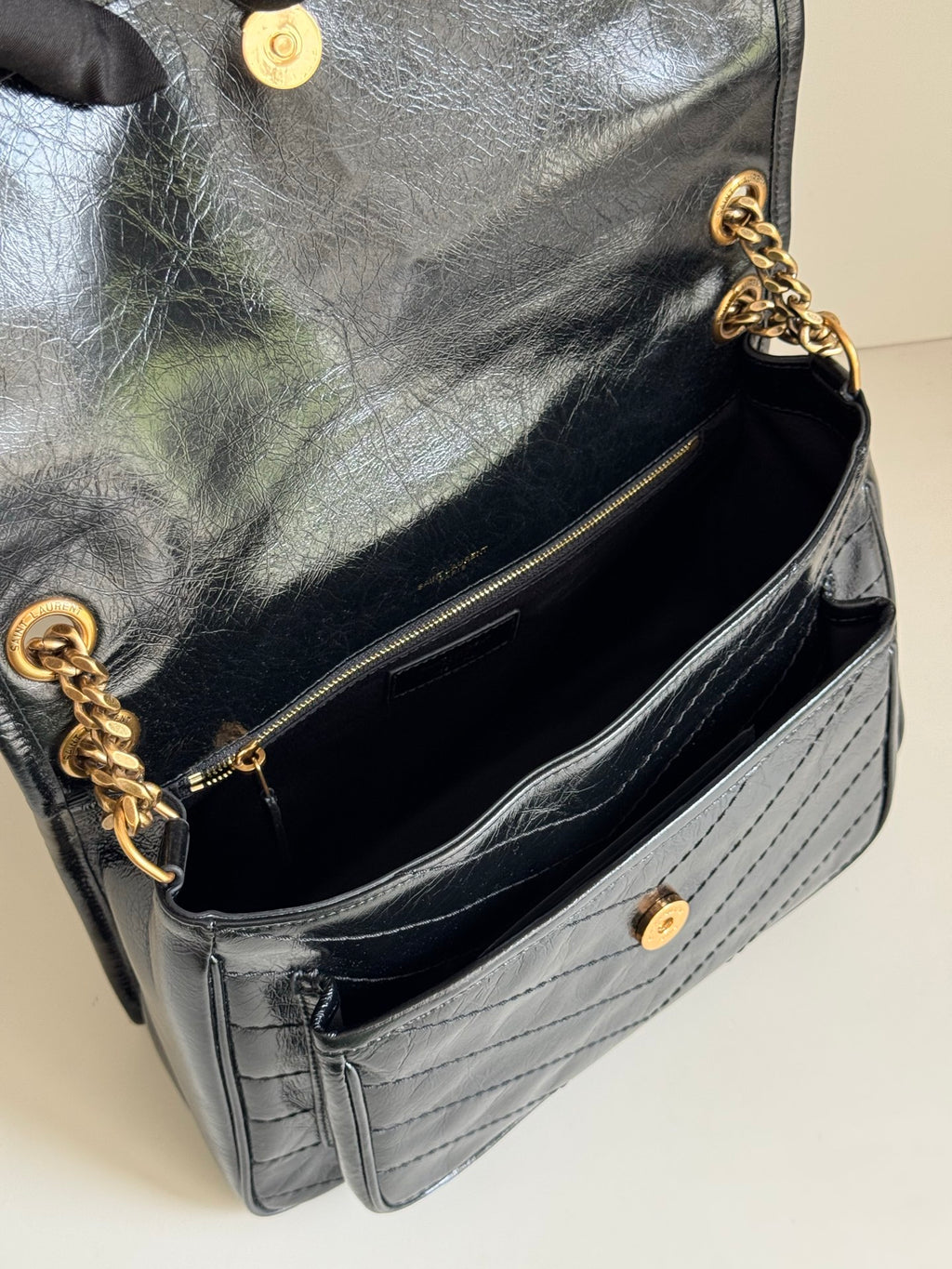 YSL bag interior with dark lining and gold chain strap, quilted leather exterior