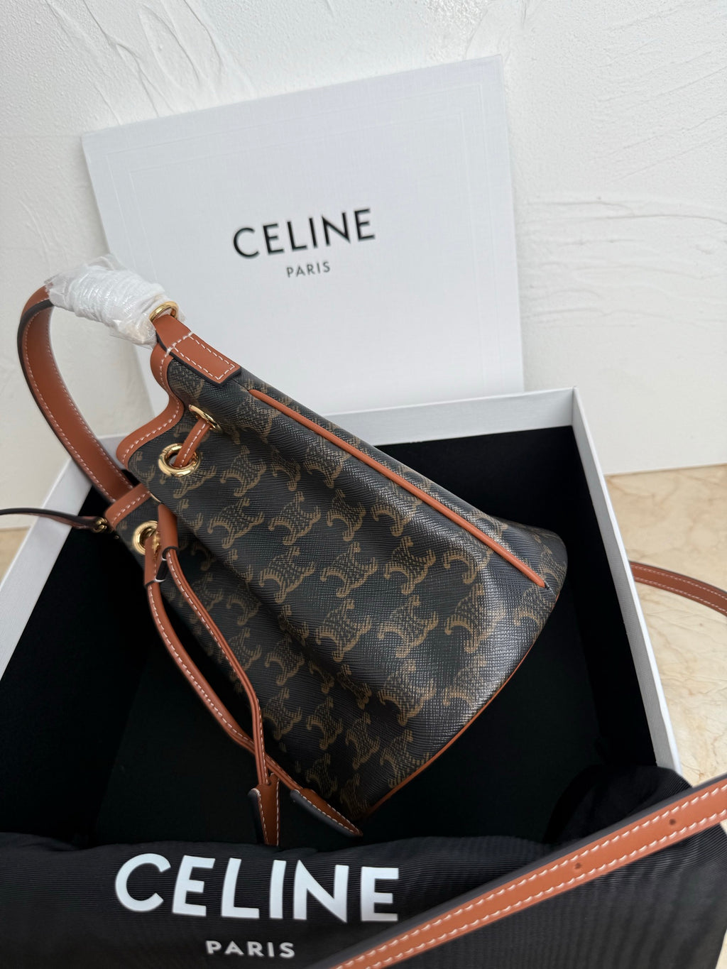 MiuMiu bag, side view monogram bucket bag with tan leather strap and stitched trim