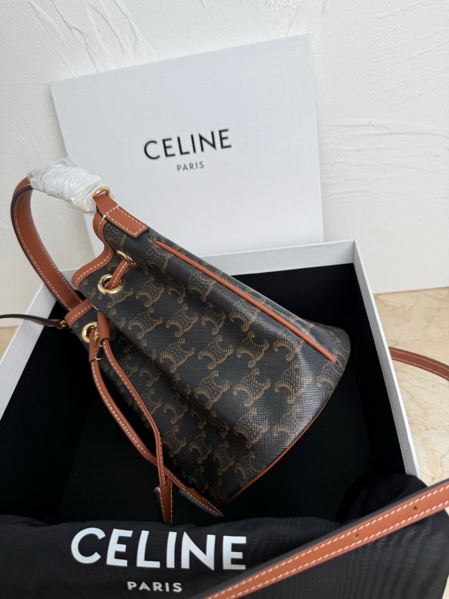 MiuMiu bag, side view monogram bucket bag with tan leather strap and stitched trim