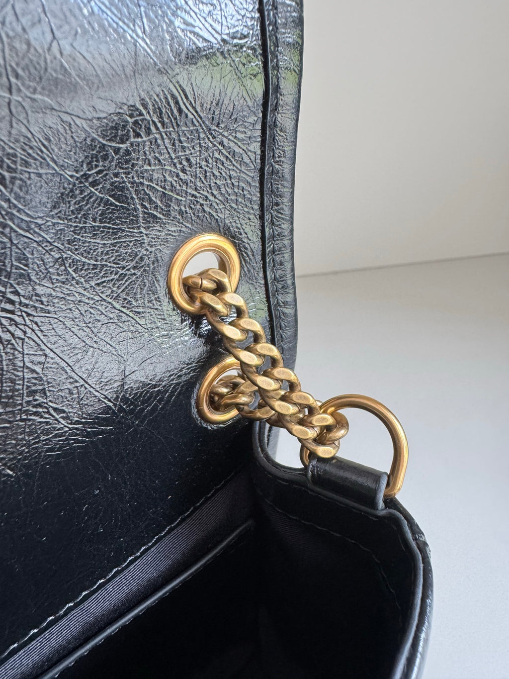 Black leather bag with gold chain ring clasp and inner flap edge detail