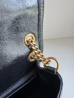 Black leather bag with gold chain ring clasp and inner flap edge detail