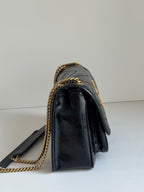 Black leather mini shoulder bag with gold chain strap and structured flap profile