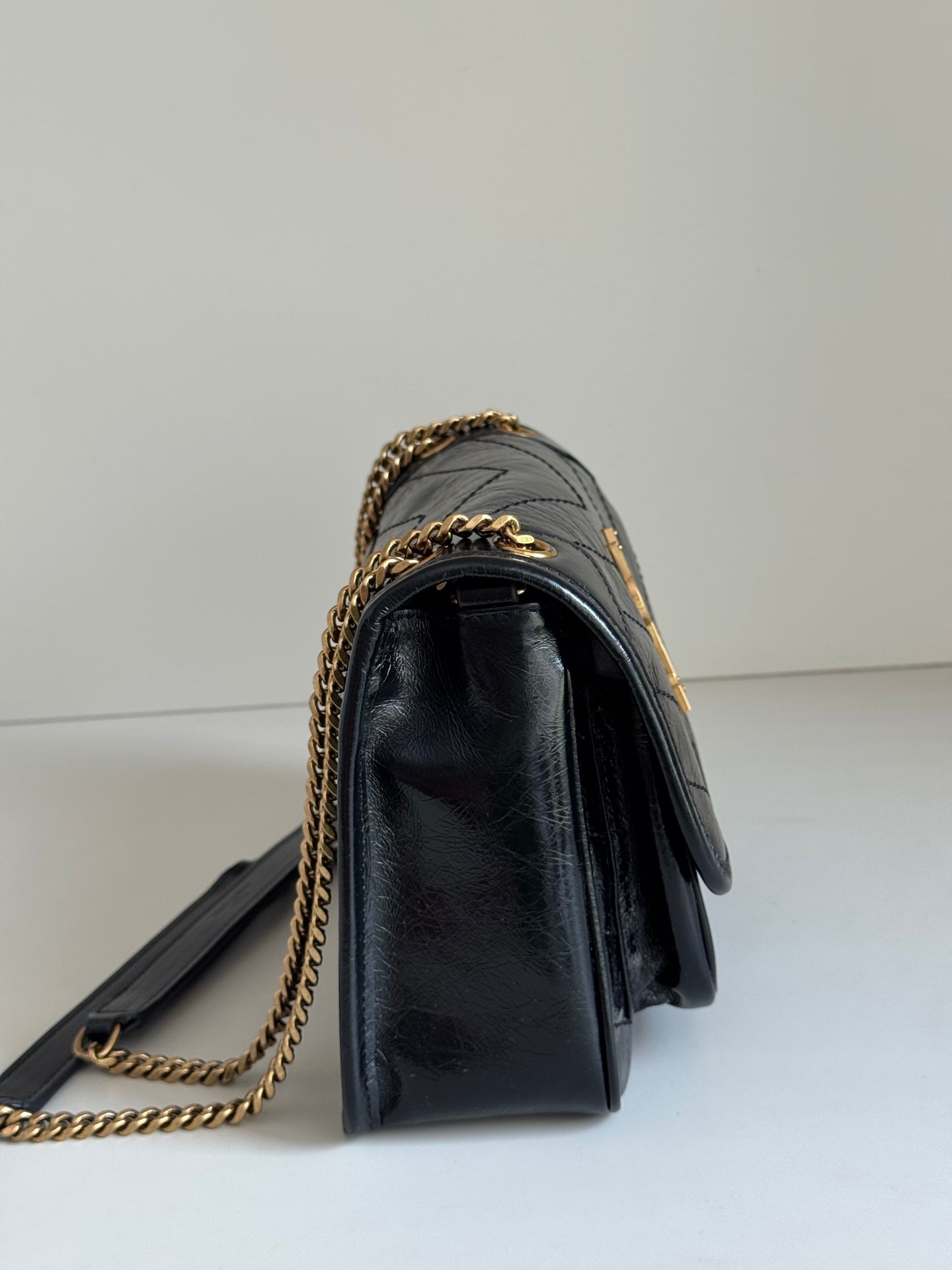Black leather mini shoulder bag with gold chain strap and structured flap profile