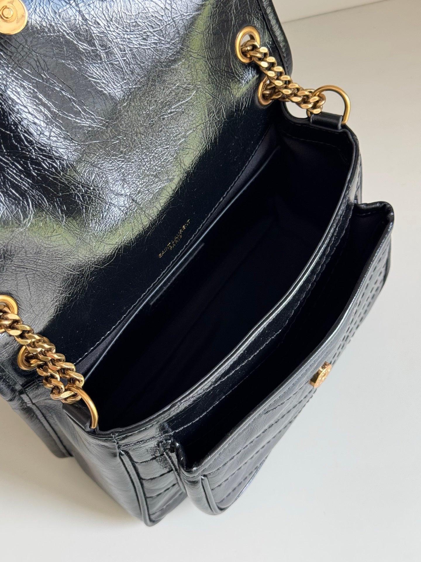 Black leather mini bag with open top interior and gold chain strap attachment