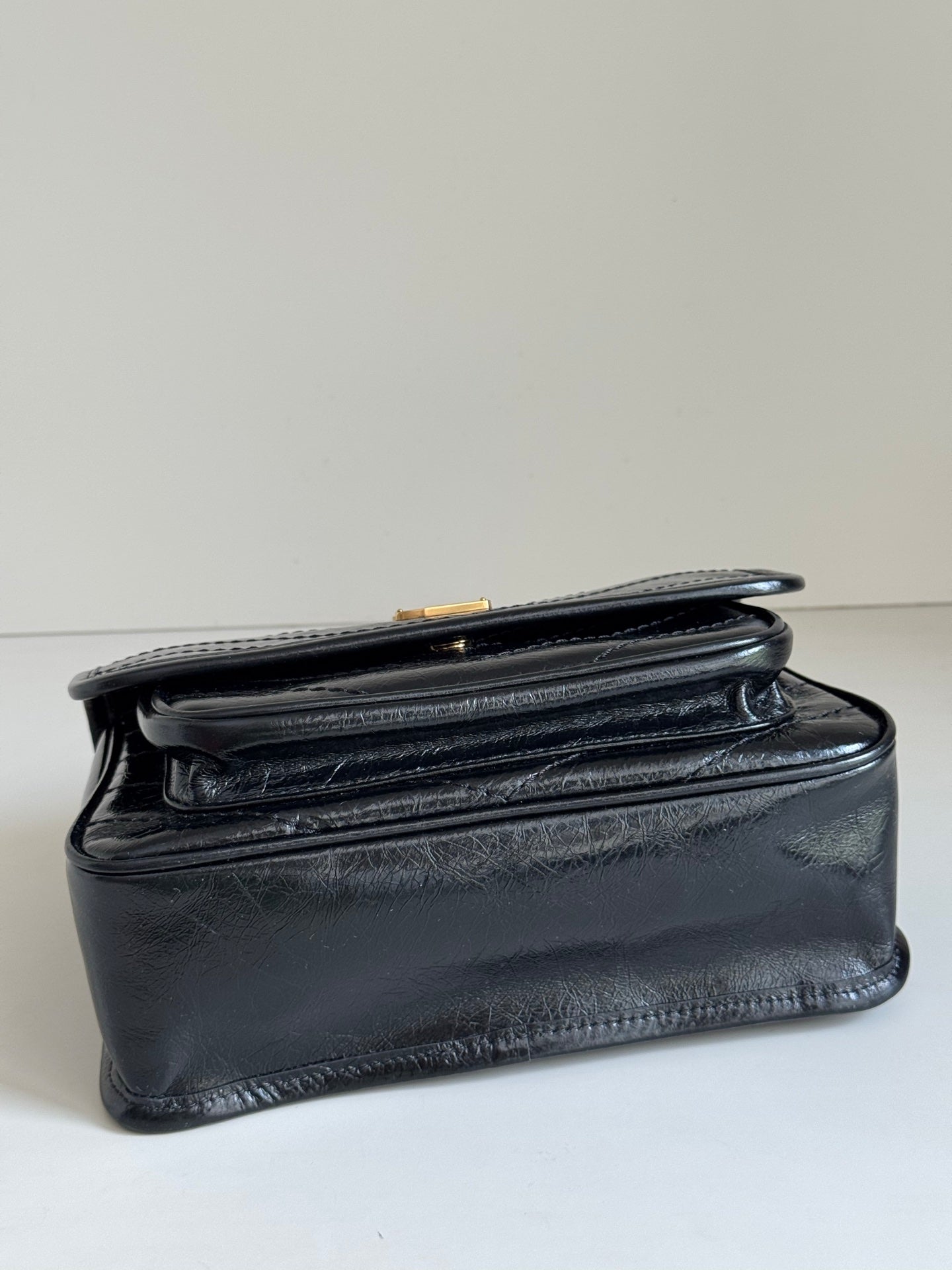 Black leather shoulder bag with structured shape, front flap seam, and top edge