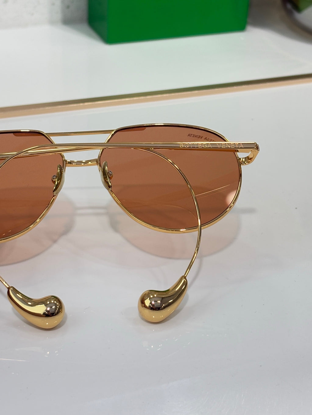 Gold-tone sunglasses side view with brown lenses and hinge detail