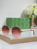Gucci round sunglasses with gold-tone frame and red-tinted lenses