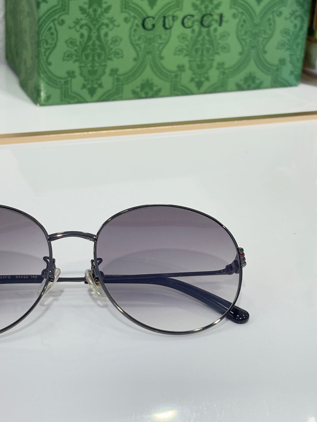 Gucci round sunglasses close-up with dark frame and purple gradient lenses