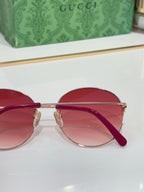 Gucci round sunglasses close-up with red frame and pink gradient lenses