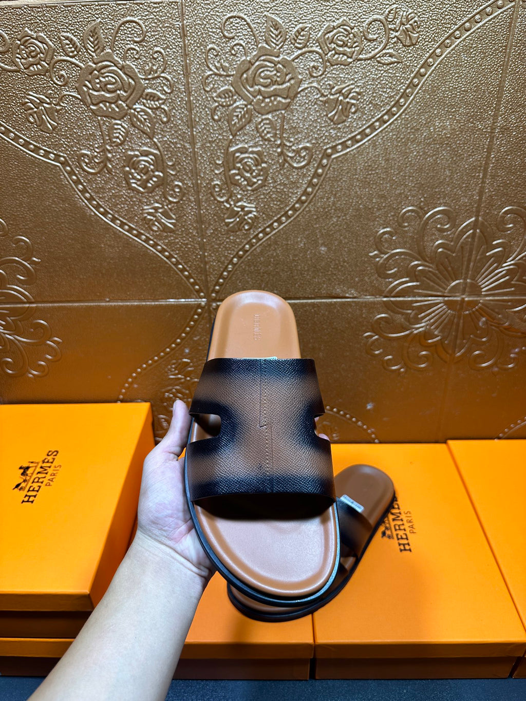 Hermes dark blue leather slide sandals held up, wide H-style strap visible