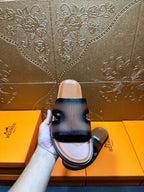Hermes dark blue leather slide sandals held up, wide H-style strap visible
