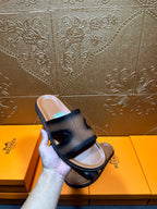 Hermes dark blue leather slide sandals held in hand, wide front strap