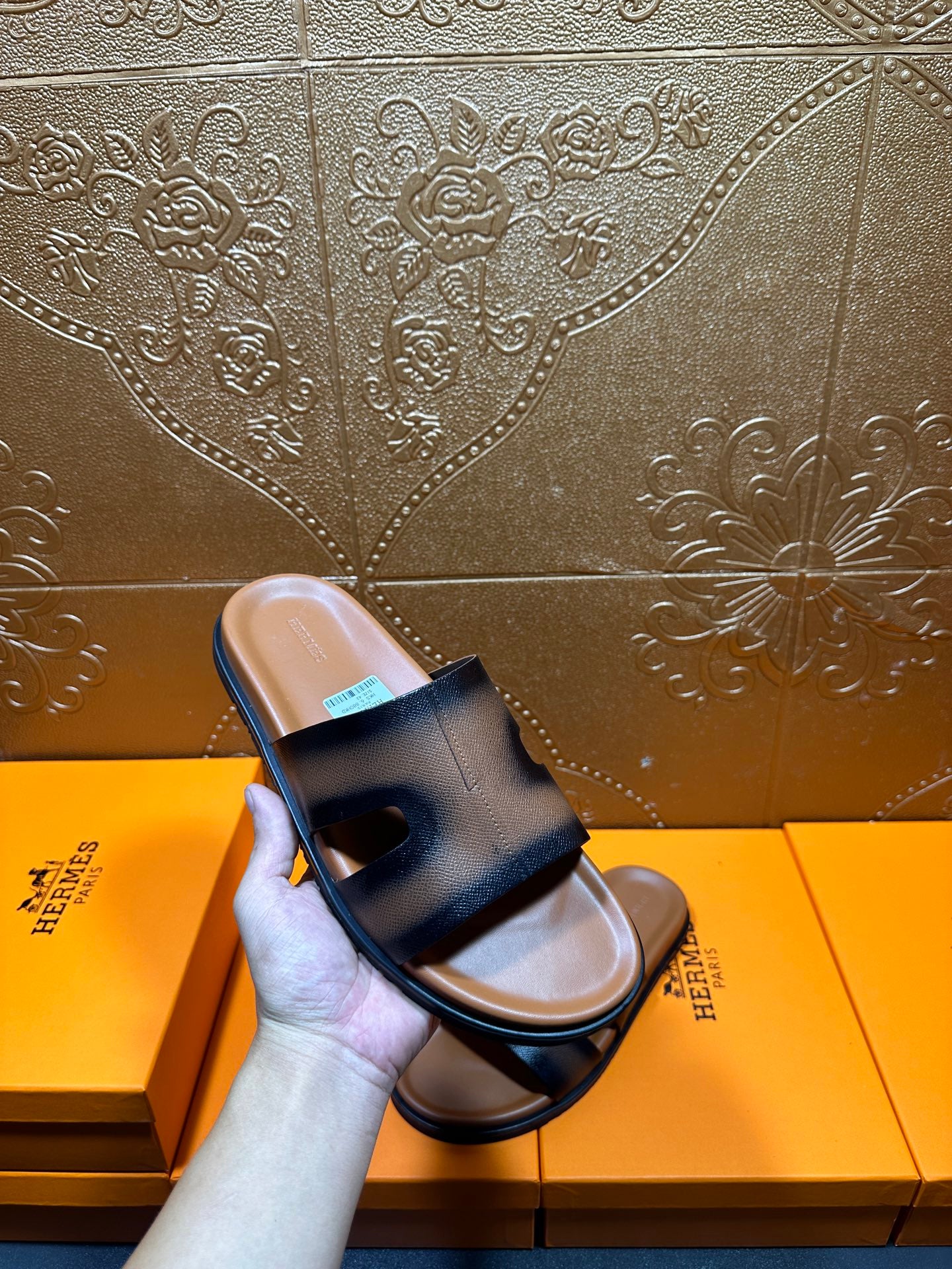 Hermes dark blue leather slide sandals held in hand, wide front strap