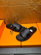 Hermes dark leather slide sandals with wide strap and open toe, pair view