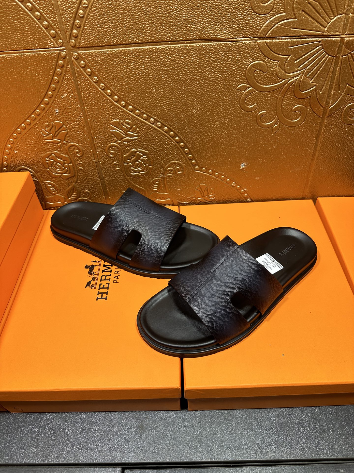 Hermes dark leather slide sandals with wide strap and open toe, pair view