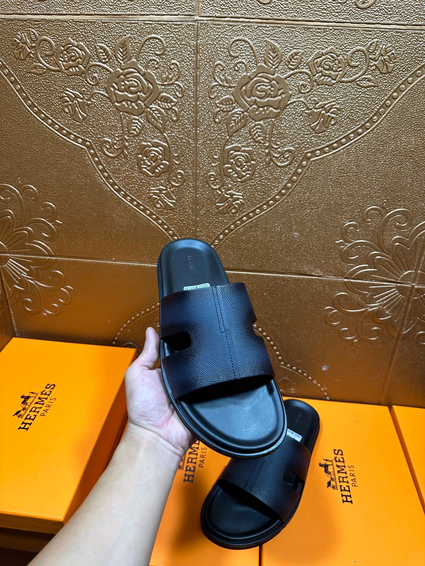 Hermes dark leather slide sandal held up, wide strap and open toe