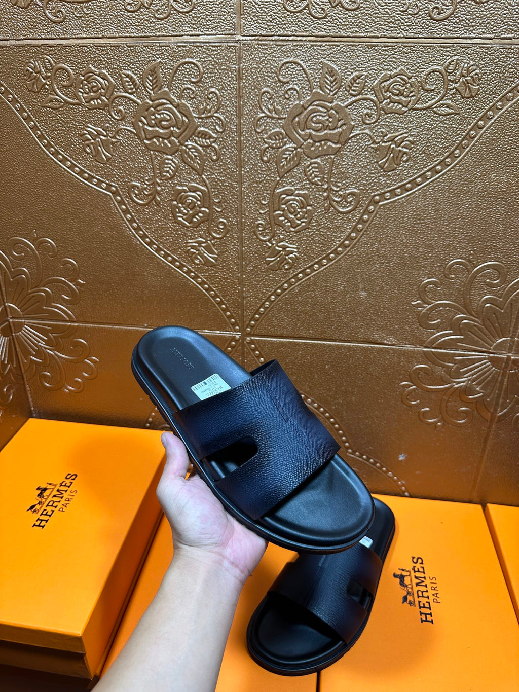 Hermes dark leather slide sandal in hand, wide strap and open toe
