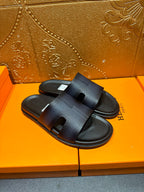 Hermes dark leather slide sandals with wide strap and open toe, angled view