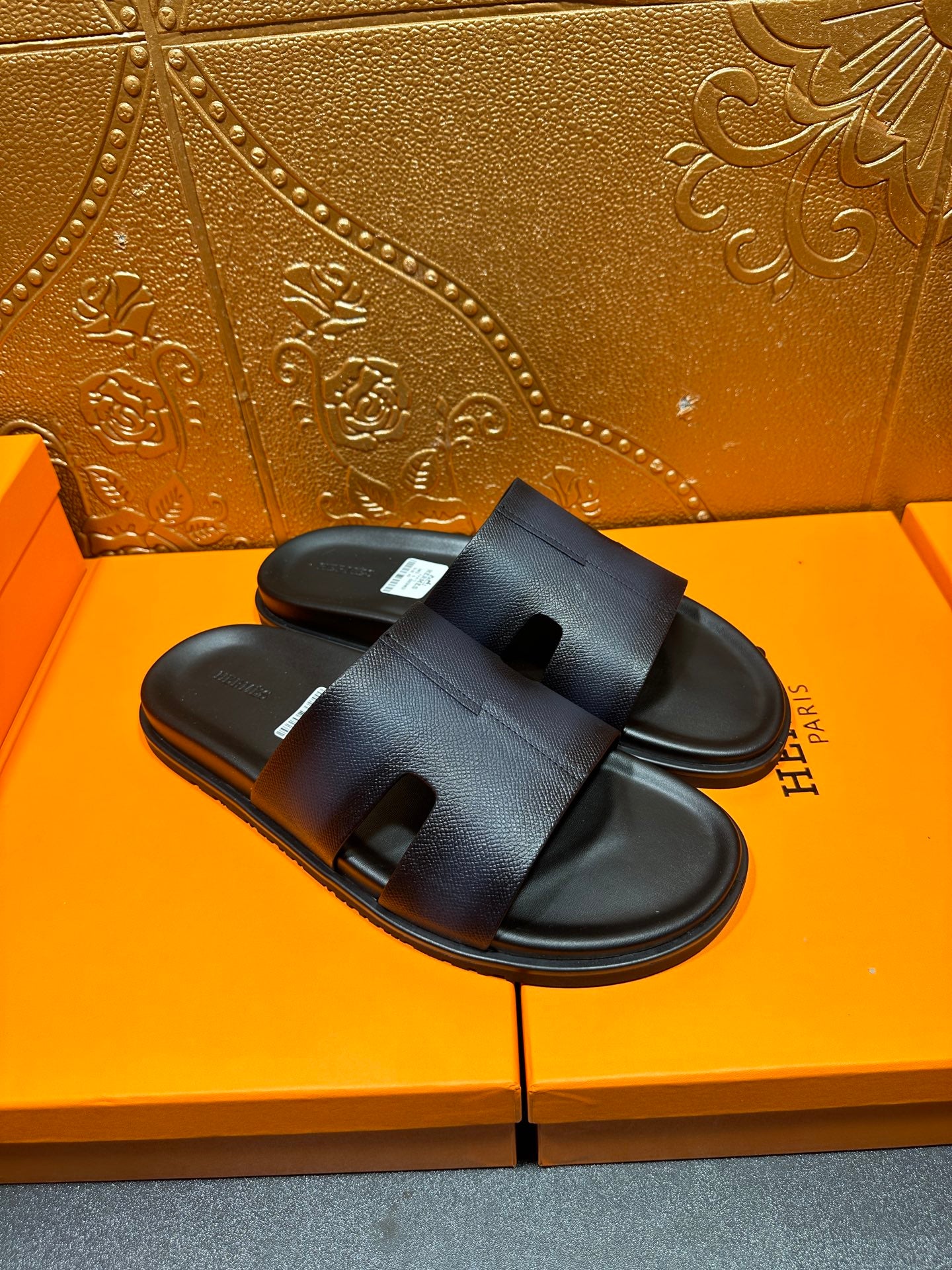 Hermes dark leather slide sandals with wide strap and open toe, angled view