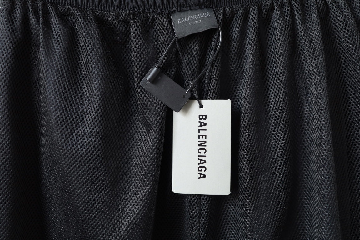 Black pants with perforated fabric and BALENCIAGA tag hanging from seam.