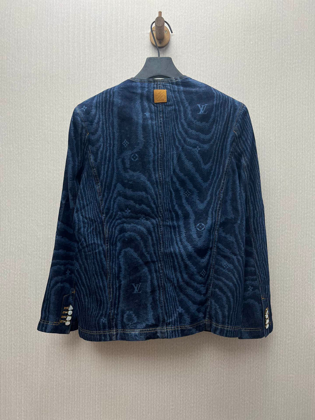Long-sleeve blue denim jacket with back button closure and monogram-style print