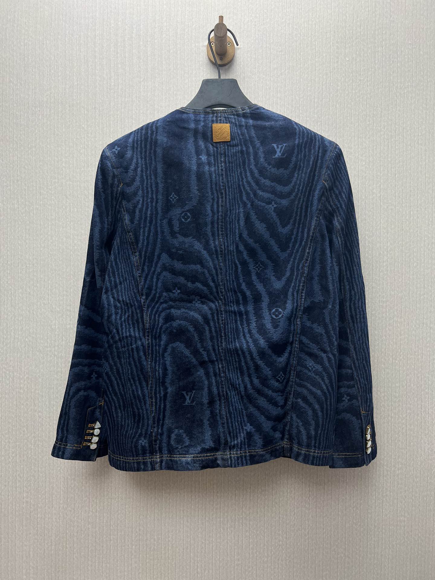 Long-sleeve blue denim jacket with back button closure and monogram-style print