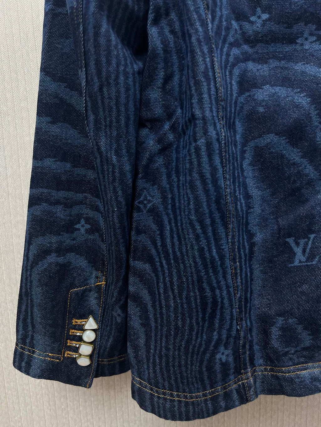 Blue denim jacket sleeve cuffs with snap closure and stitched detailing
