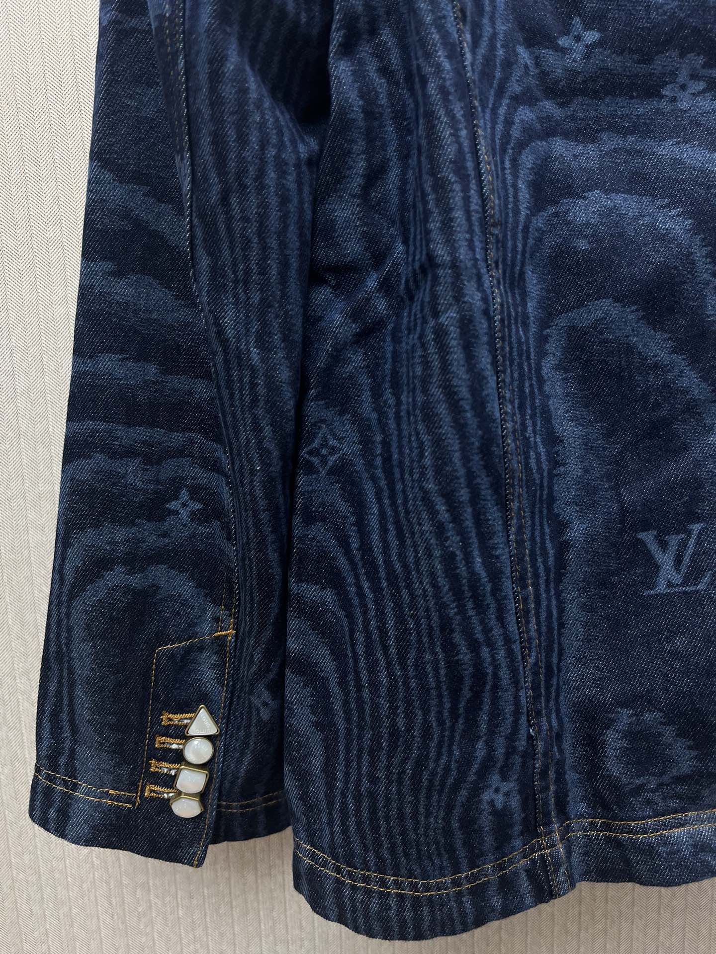 Blue denim jacket sleeve cuffs with snap closure and stitched detailing