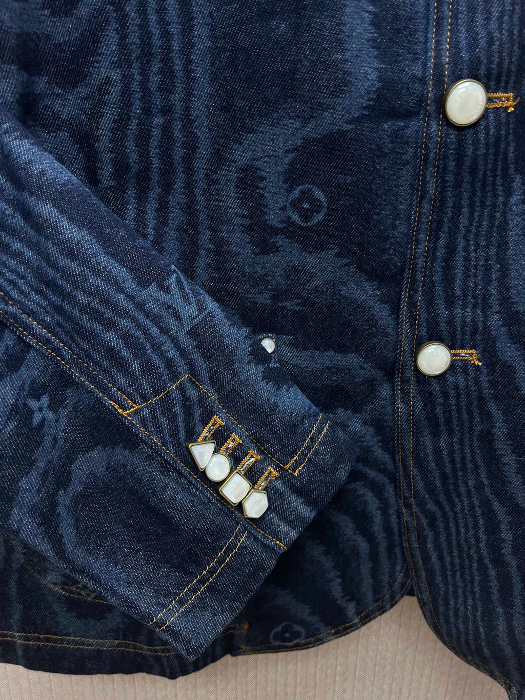 Blue denim jacket sleeve seam with snap buttons and stitched trim