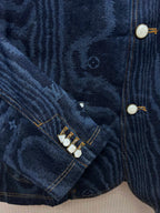 Blue denim jacket sleeve seam with snap buttons and stitched trim