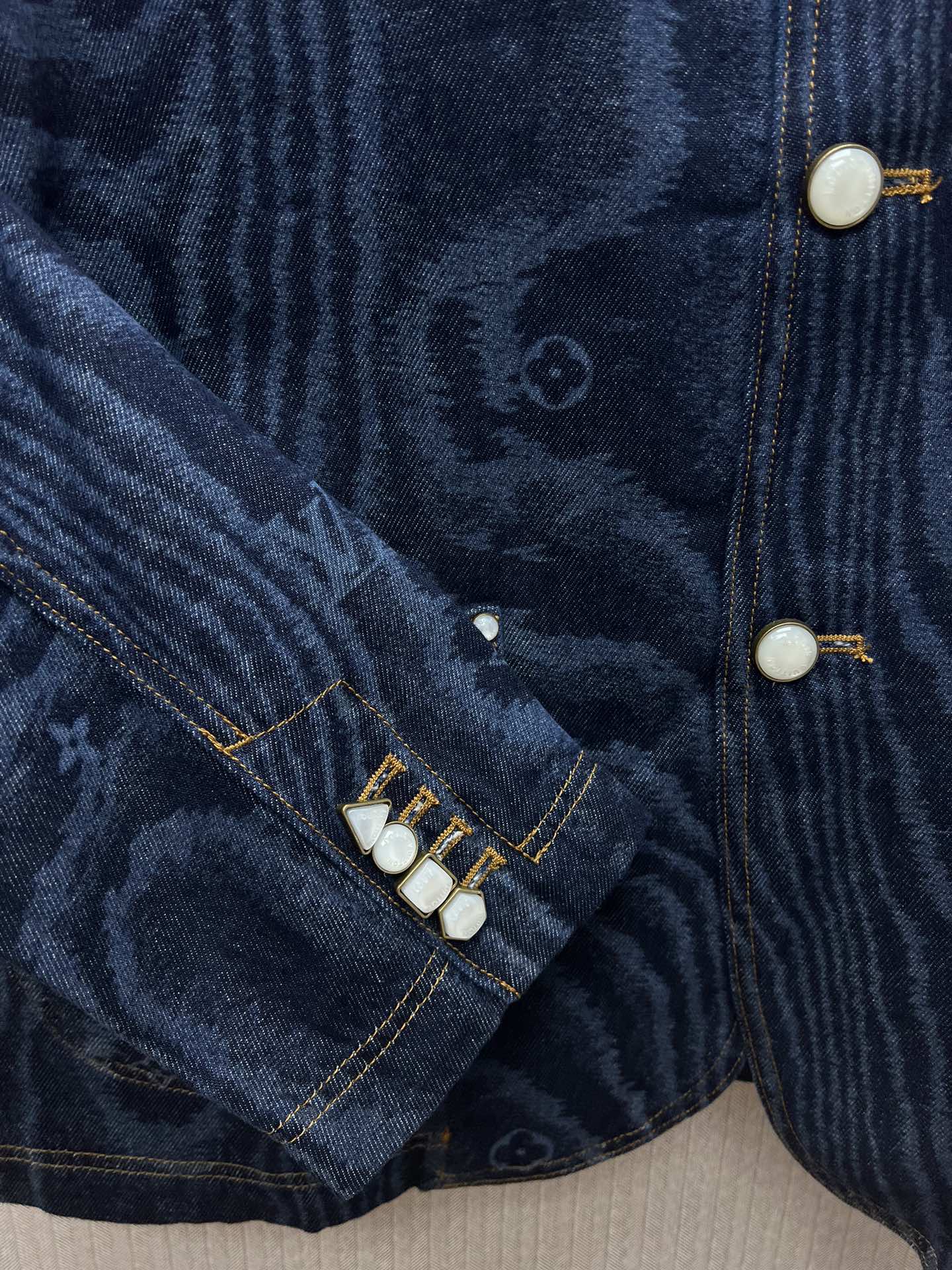 Blue denim jacket sleeve seam with snap buttons and stitched trim