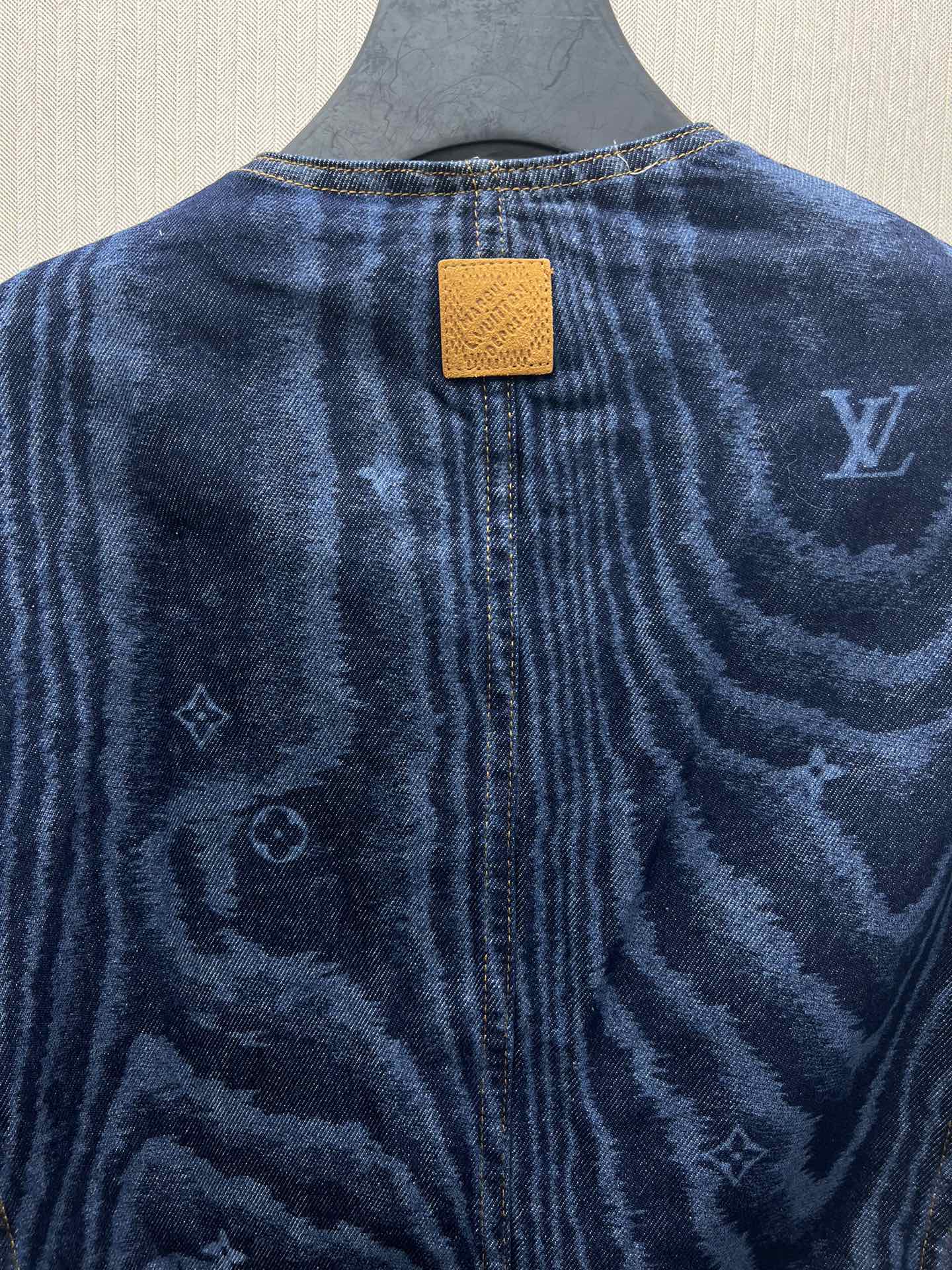 Back of blue denim jacket with rectangular leather-look patch