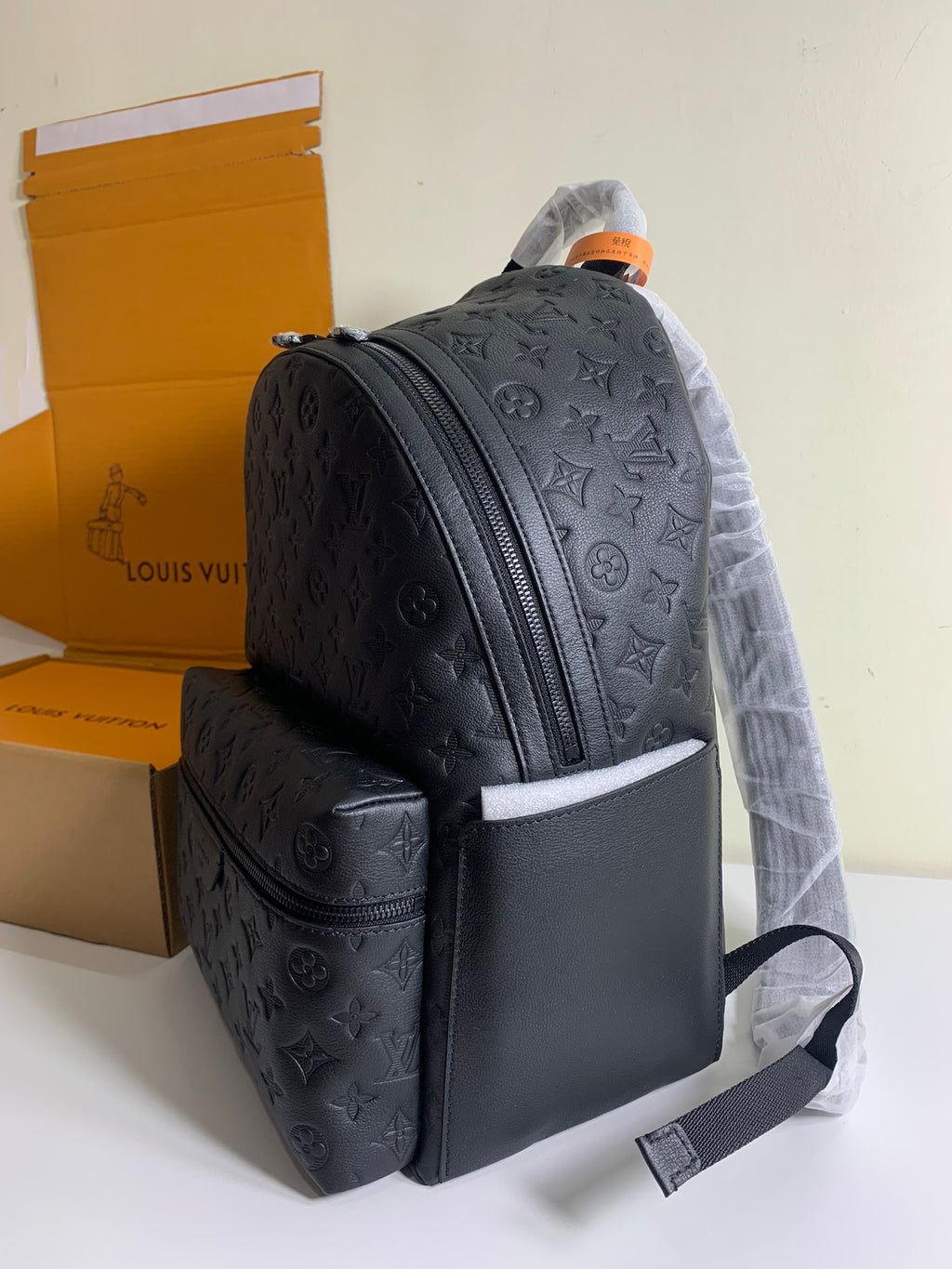 Louis Vuitton monogram backpack with front zipper and wide front panel, dark embossed leather.
