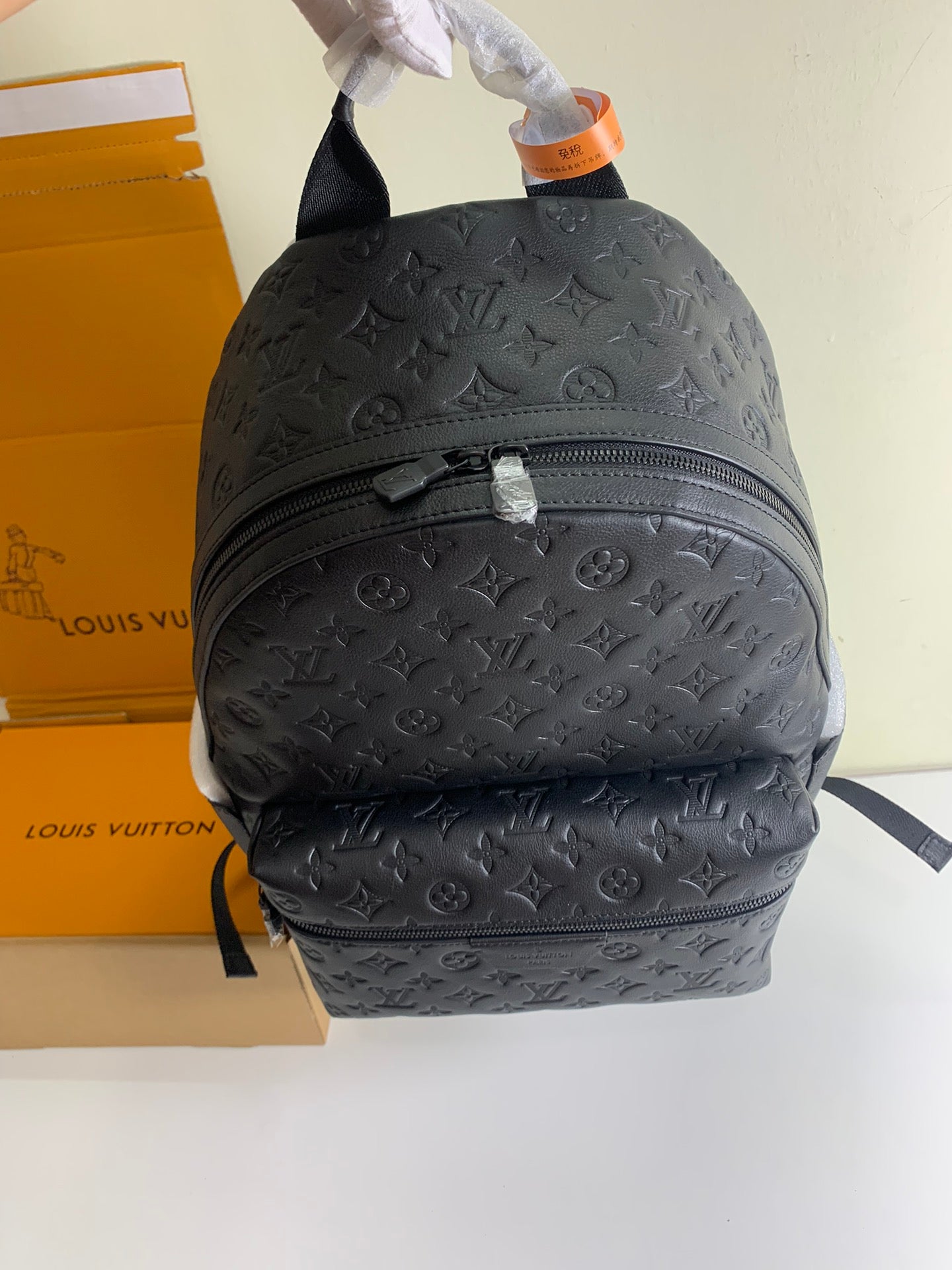 Louis Vuitton monogram backpack with top handle and rounded front, dark embossed leather.