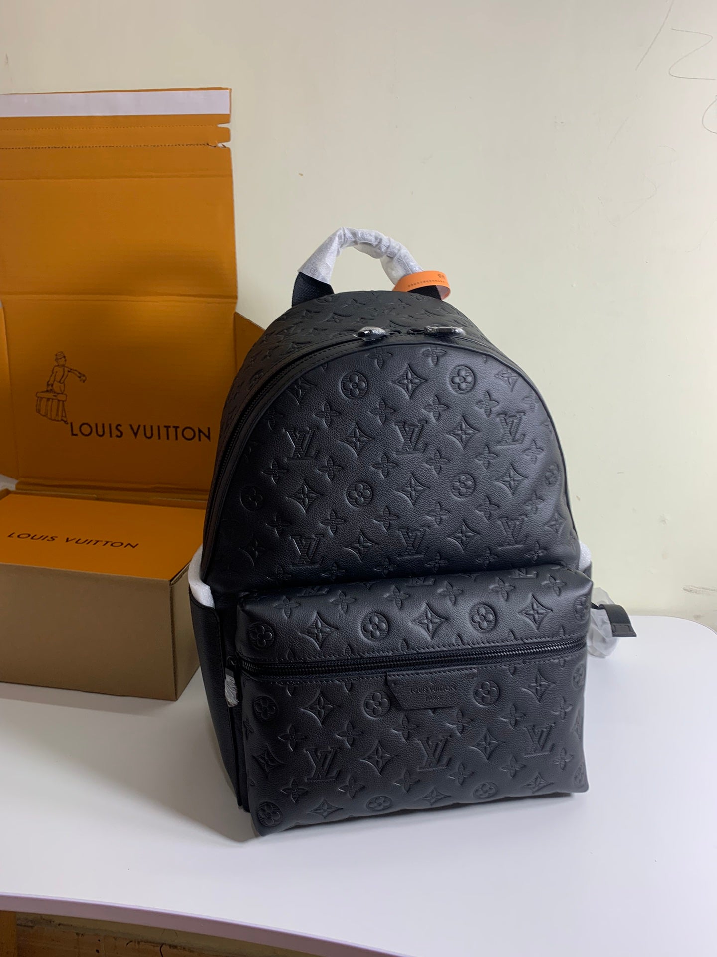 Louis Vuitton monogram backpack with top handle and front pocket, black embossed leather look.