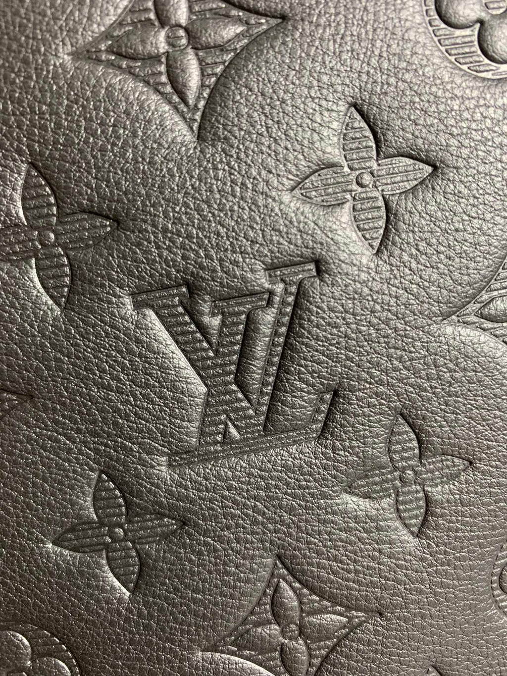 Louis Vuitton monogram leather close-up showing embossed pattern on textured surface.