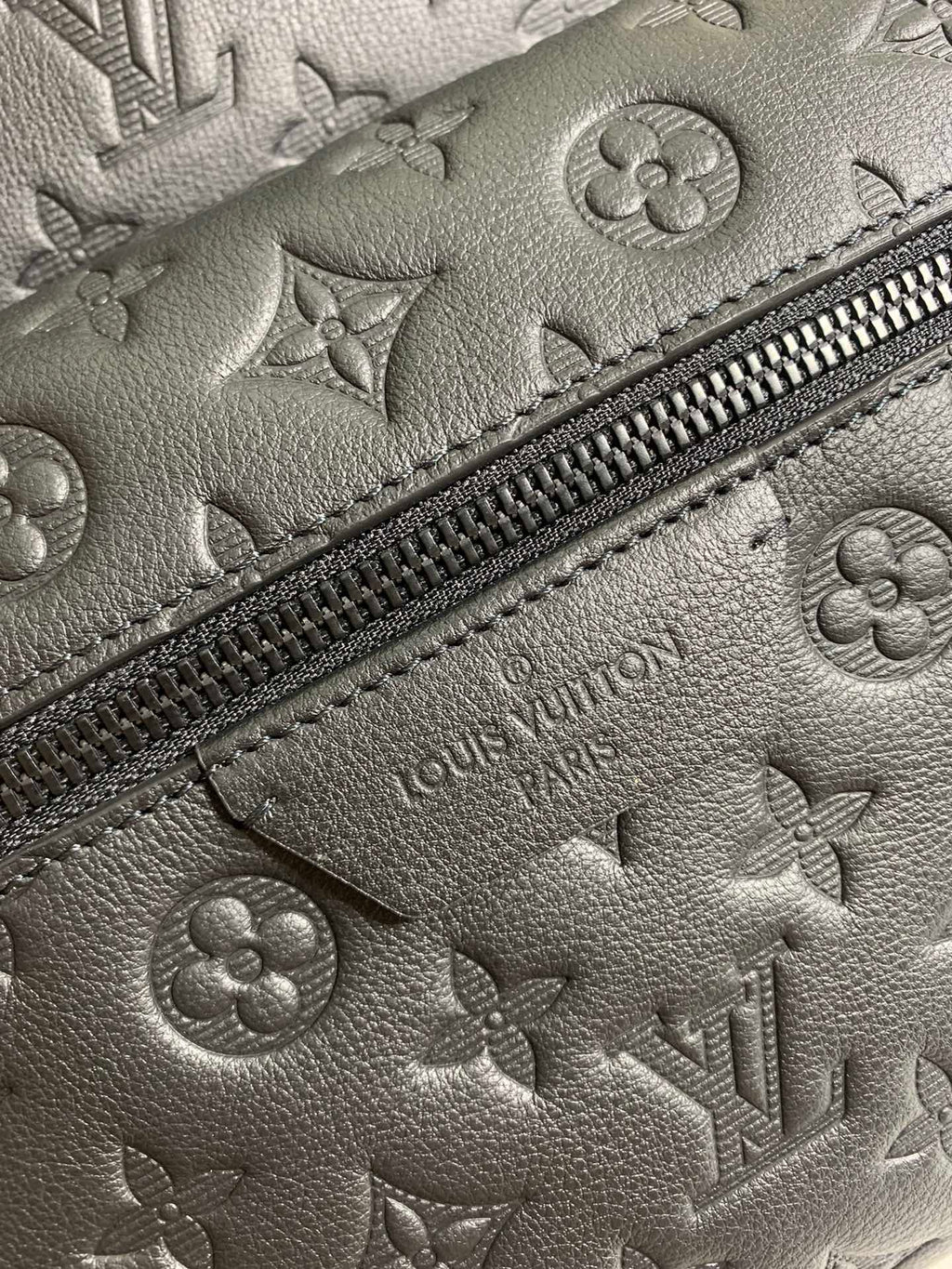Louis Vuitton monogram leather close-up with zipper trim and embossed LV details.