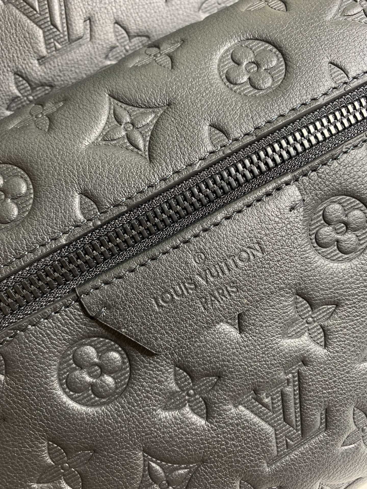 Louis Vuitton monogram leather close-up with zipper trim and embossed LV details.