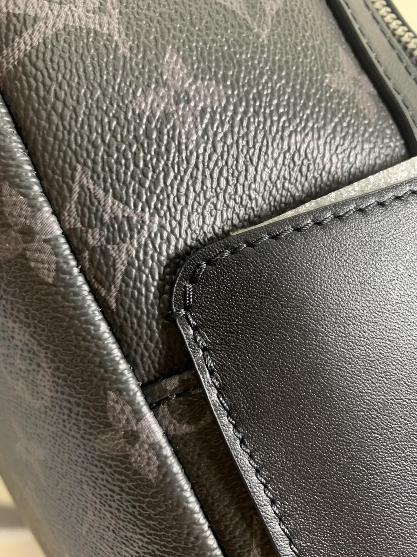 Monogram backpack close-up of textured leather trim and stitched zipper edge